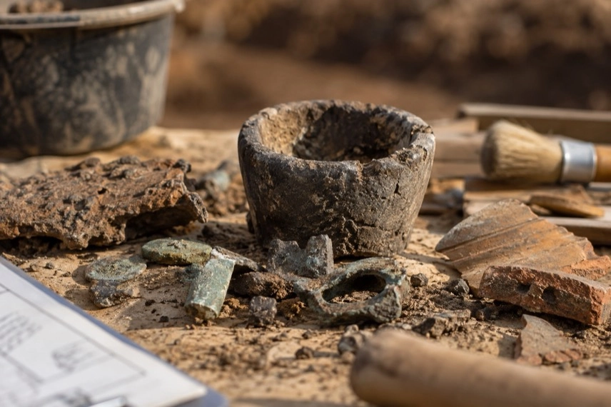Archäologische Grabungsfläche mit Schmelztiegel, Metallstücken und Keramik aus der Römischen Kaiserzeit