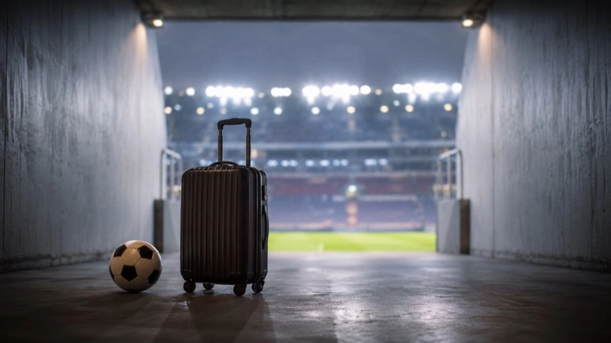 Leerer Spielertunnel in einem Fußballstadion mit Reisekoffer und Ball als Symbol für einen Transfer im Profifußball