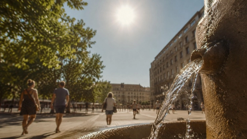 Menschen im Schatten einer Innenstadt bei großer Hitze, digitale Temperaturanzeige zeigt hohe Sommerwerte in Deutschland.