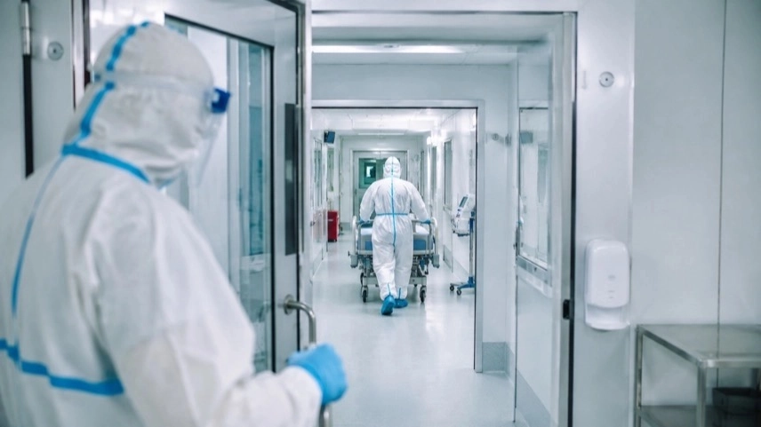 Medizinisches Personal in Schutzanzügen vor Isolationsstation für Ebola-Patient in moderner Spezialklinik