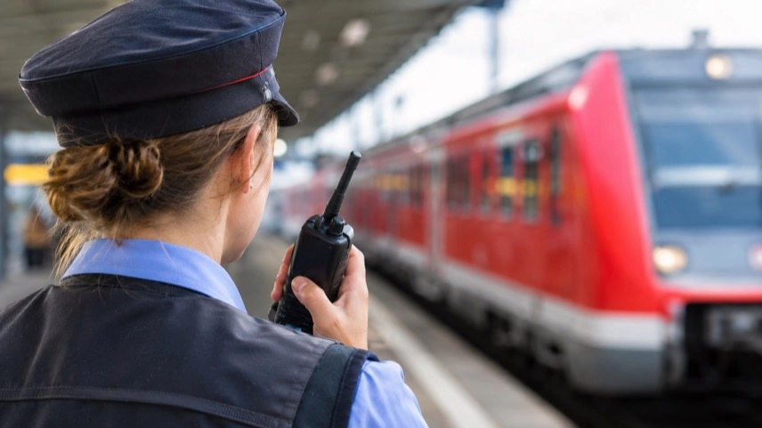 Zugbegleiter an einem Bahnsteig neben einem Regionalzug im Regionalverkehr
