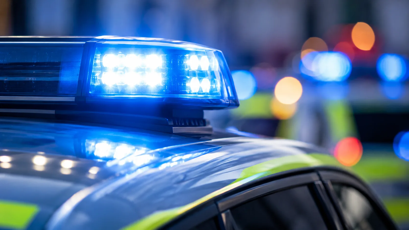 Blaues Polizeiblaulicht auf einem neutralen Polizeifahrzeug vor unscharfem Hintergrund ohne erkennbare Ortsmerkmale.