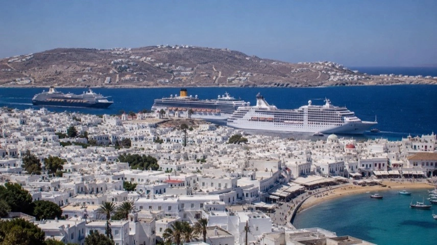 Kreuzfahrtschiffe vor griechischer Insel mit dichter Bebauung und starkem Tourismus an der Mittelmeerküste
