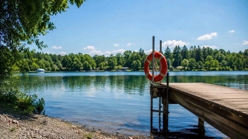 Leerer Badesee mit Steg und Rettungsring bei sommerlichem Wetter während der Badesaison in Deutschland