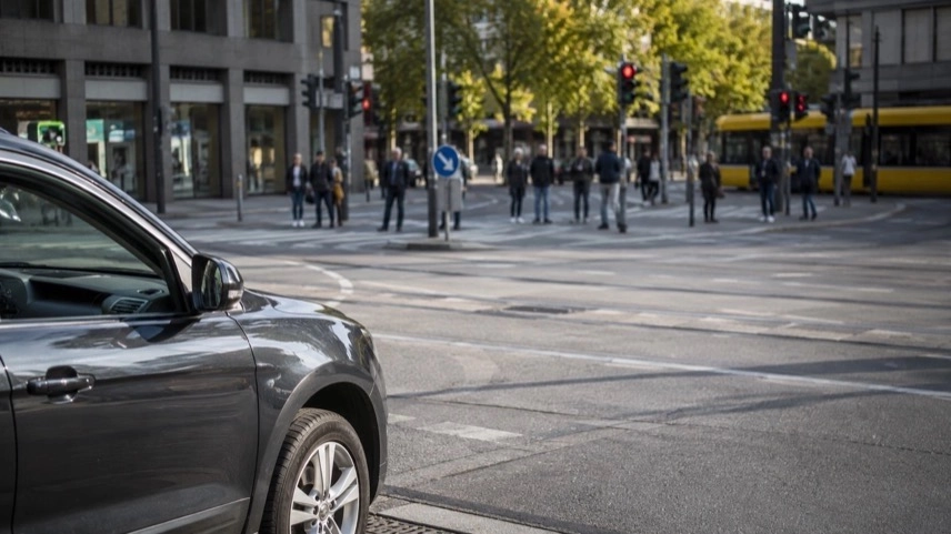 Innerstädtische Kreuzung mit Straßenbahnschienen und wartenden Fußgängern am Verkehrsknotenpunkt in Stuttgart