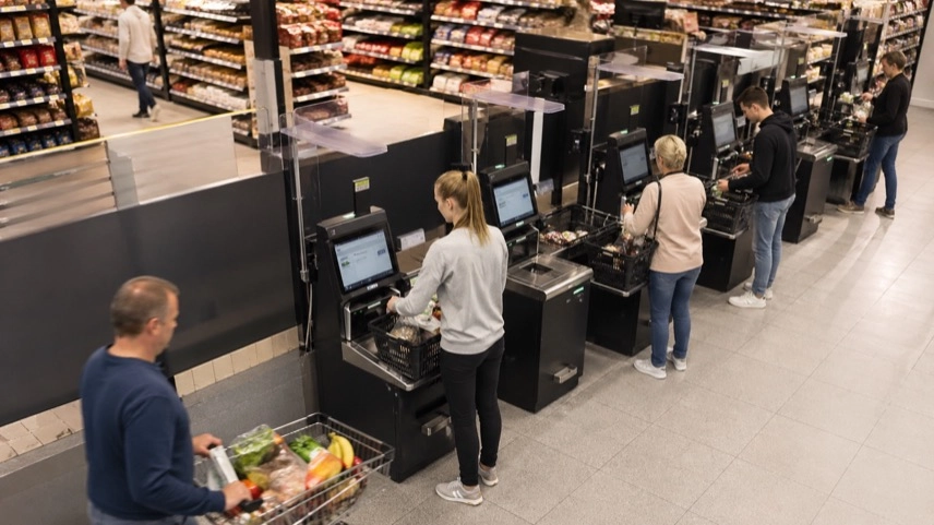 Supermarkt mit Selbstbedienungskassen und Kunden beim Scannen von Waren, Einkaufsbereich mit SB-Kassen im Einzelhandel