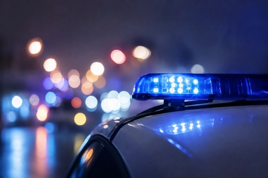 Generisches Polizeifahrzeug mit eingeschaltetem Blaulicht vor neutralem dunklem Hintergrund