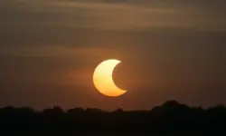 Symbolbild einer partiellen Sonnenfinsternis am 21. September 2025 mit tiefstehender Sonne über einem Horizont, fotorealistisch nachgestellt.