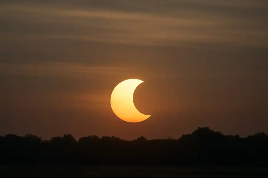 Symbolbild einer partiellen Sonnenfinsternis am 21. September 2025 mit tiefstehender Sonne über einem Horizont, fotorealistisch nachgestellt.