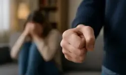 häusliche Gewalt: Nachgestellte Szene mit erhobener Faust im Vordergrund, unscharfe Frau im Hintergrund, Darstellung zum Gewalthilfegesetz.