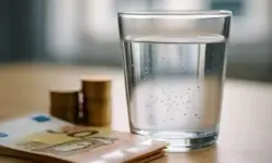 Glas Wasser mit Mikroplastik-Partikeln und Euro-Geldscheinen – Darstellung der Finanzierung des Bruchsaler Startups Klar2O.