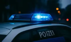 Ein Polizeiauto mit eingeschaltetem blauen Blaulicht steht auf einer Straße in der Abenddämmerung.