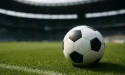 Ein Fußball liegt auf einem grünen Rasen in einem großen, leeren Stadion bei Tageslicht.