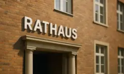 Eingang eines modernen Rathauses aus rotem Backstein mit Säulen und großen weißen Buchstaben „Rathaus“.