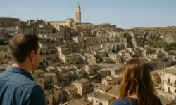 Historische süditalienische Stadt mit alten Steinhäusern, Menschen im Vordergrund und sonnigem Himmel im Hintergrund.