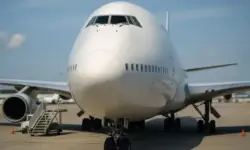 Frontansicht einer großen Boeing 747 auf einem Flughafenrollfeld bei Tageslicht, mit klarer Tiefenschärfe und sichtbarem Fahrwerk.