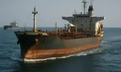 Rostiger Öltanker fährt auf ruhiger See, im Hintergrund ein weiterer Frachter unter klarem Himmel.