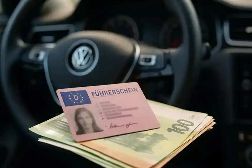 Ein deutscher Führerschein liegt auf mehreren Euro-Geldscheinen im Innenraum eines Autos.