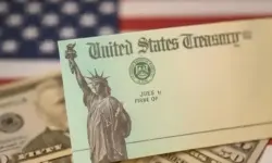 Nahaufnahme eines US-Treasury-Schecks auf Dollar-Scheinen mit unscharfer US-Flagge im Hintergrund.