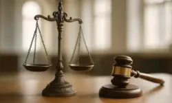 Bronzene Waage und Holzhammer auf einem Tisch in einem hellen Raum mit unscharfem Hintergrund.