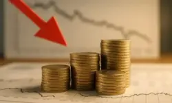 Gestapelte Euro-Münzen vor einem Diagramm mit fallender Kurve und rotem Abwärtspfeil.