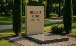 Ein heller Sandstein-Grabstein im Park, umgeben von Zypressen und gepflegtem Rasen, mit sanfter Tiefenschärfe bei Tageslicht.