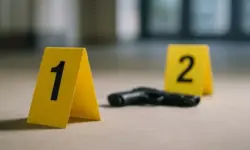 Tatort-Szene mit gelben Markierungen und einer Pistole auf dem Boden, unscharfer Hintergrund, Symbolfoto.