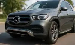 Silbergrauer Mercedes-SUV steht bei Tageslicht auf einer asphaltierten Straße mit Bäumen im Hintergrund.