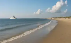 Fähre vor der Küste von Norderney mit Strand, Meer und blauem Himmel – Darstellung eines modernen Inselurlaubs.