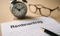 Rentendebatte in Deutschland mit Uhr, Brille und Rentenantrag auf einem Schreibtisch, sinnbildlich für das höhere Rentenalter.