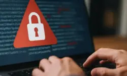 Symbolfoto eines Computerbildschirms mit rotem Warnsymbol und Händen auf Tastatur – Darstellung eines Cyberangriffs auf Salesforce-Daten.