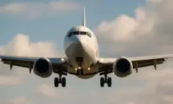 Frontansicht eines zweistrahligen Passagierflugzeugs beim Landeanflug mit ausgefahrenem Fahrwerk und leicht bewölktem Himmel im Hintergrund.