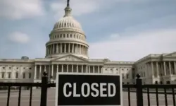 Das US-Kapitol in Washington, im Vordergrund ein Zaun mit einem Schild, das eine Schließung andeutet, bei Tageslicht aufgenommen.