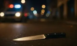 Ein Messer liegt auf einer nächtlich beleuchteten Straße, im Hintergrund sind unscharfe Polizeilichter zu sehen.