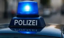 Nahaufnahme einer blauen Polizeisirene auf dem Dach eines Einsatzfahrzeugs, das Blaulicht leuchtet deutlich vor unscharfem Stadt­hintergrund.