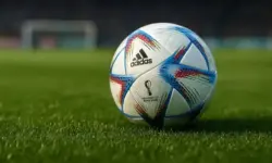 Nahaufnahme eines Fußballs auf grünem Rasen in einem leeren Stadion mit unscharfem Hintergrund.