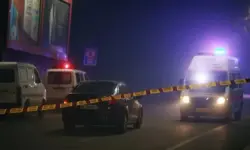 Leere nächtliche Straße mit Einsatzfahrzeugen, Blaulicht und Absperrband vor beleuchteten Werbetafeln.