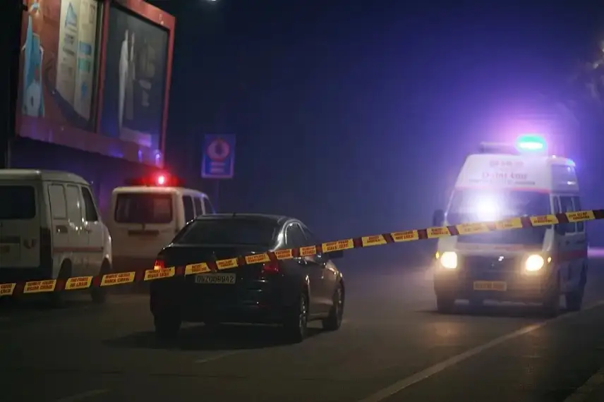 Leere nächtliche Straße mit Einsatzfahrzeugen, Blaulicht und Absperrband vor beleuchteten Werbetafeln.