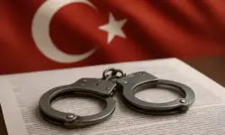 Handschellen auf einem Dokument mit unscharfer türkischer Flagge im Hintergrund.