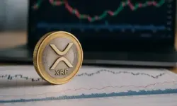 XRP-Münze auf Finanzcharts mit unscharfem Laptop im Hintergrund, der Kursdiagramme zeigt.