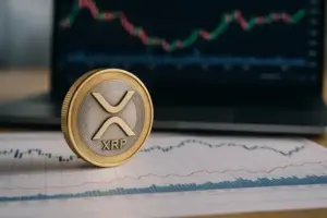XRP-Münze auf Finanzcharts mit unscharfem Laptop im Hintergrund, der Kursdiagramme zeigt.
