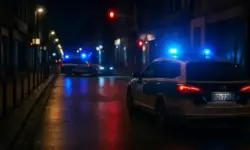 Polizeifahrzeuge mit eingeschaltetem Blaulicht stehen nachts auf einer leeren, nassen Stadtstraße.