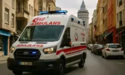 Türkischer Krankenwagen fährt bei Tageslicht durch eine enge Straße in Istanbul, umgeben von Wohnhäusern und Autos.