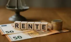 Holzwürfel mit dem Wort „Rente“ auf Euro-Scheinen, daneben gestapelte Münzen und eine unscharfe Waage im Hintergrund.