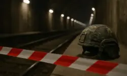 Militärhelm in Tarnmuster liegt neben Absperrband auf einem Bahnsteig in einem U-Bahntunnel, Schienen und Lichter verlaufen unscharf in die Tiefe.