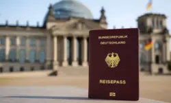 Deutscher Reisepass im Vordergrund vor dem unscharfen Berliner Reichstagsgebäude bei Tageslicht.