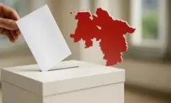 Eine Hand wirft einen leeren Stimmzettel in eine Wahlurne, im Hintergrund eine rote Silhouette der Landkarte von Niedersachsen.
