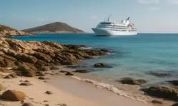 Ein Kreuzfahrtschiff liegt vor einer felsigen tropischen Insel im türkisblauen Meer bei sonnigem Wetter.