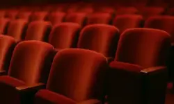 Reihen roter Samtsitze in einem Theater, fotografiert mit Tiefenschärfe und warmem Licht.