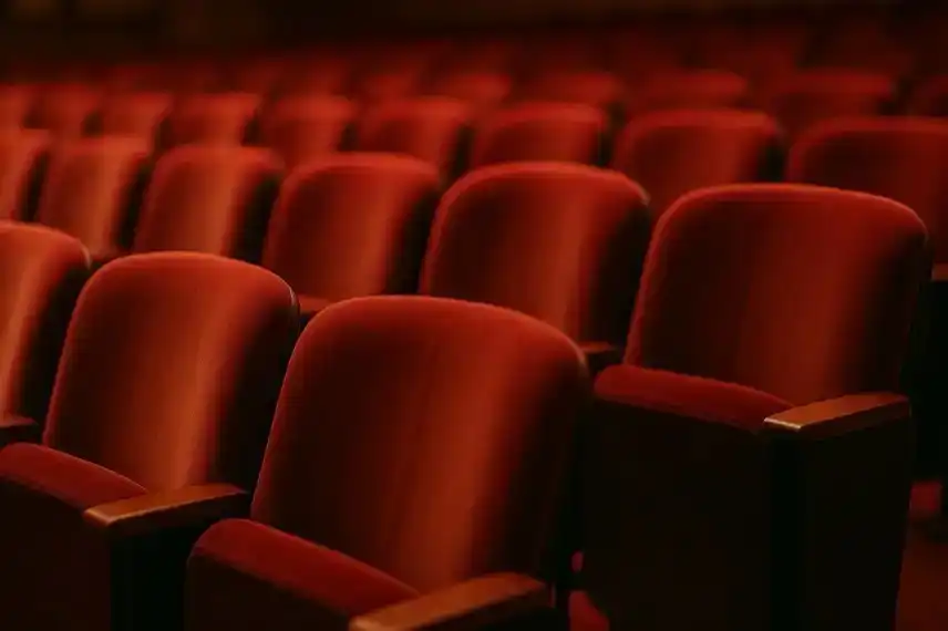 Reihen roter Samtsitze in einem Theater, fotografiert mit Tiefenschärfe und warmem Licht.